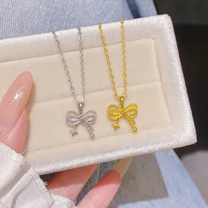 Close-up of silver and gold bow pendants with tiny star accents displayed on a velvet jewelry box