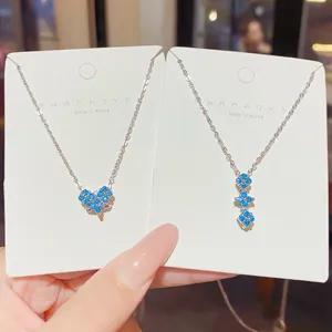 Two silver-tone chains display blue heart and floral stone pendants on white cards