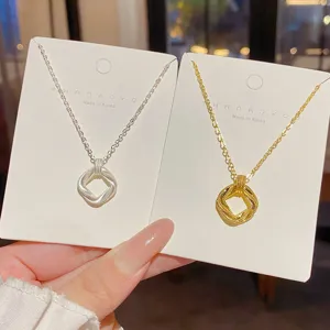 Two necklaces on display cards, with silver and gold chains and textured open square pendants