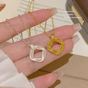 Close-up of silver and gold square woven pendants with beaded edges, displayed on a hand