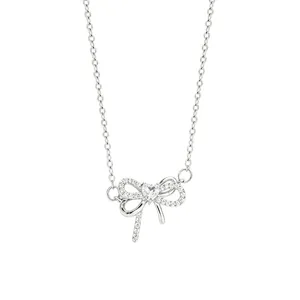 Silver-tone necklace with a pavé bow pendant and a central heart-shaped white gemstone on white