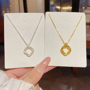 Fine chains on white display cards, with textured interwoven square pendants in silver and gold.