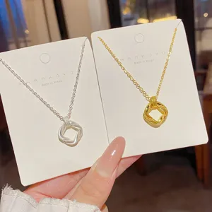 Silver and gold interlocking square pendants with fine texture, shown on necklace display cards