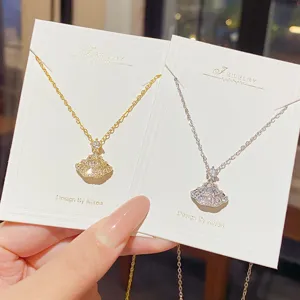 Close-up of two fan-shaped crystal pendants on fine gold and silver chains, shown on display cards