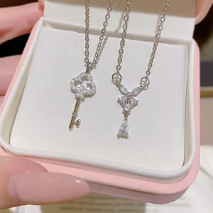 Two silver-tone titanium steel necklaces with crystal key and bow-shaped teardrop pendants