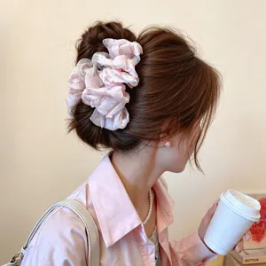 Vista lateral de una modelo con una pinza de tela rosa claro con volantes en el cabello recogido