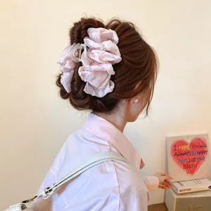 Vista lateral de un recogido castaño adornado con una gran flor de tela rosa pálido en el cabello