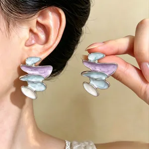Orecchini asimmetrici a strati, color lavanda, azzurro chiaro e avorio, indossati e mostrati in mano