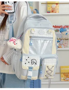 Front view of a pastel blue backpack with a clear PVC window, beige panels, and star and bear charms