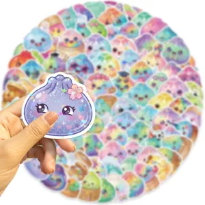 Hand holding a pastel dumpling sticker with a holographic shine, with more designs in the background