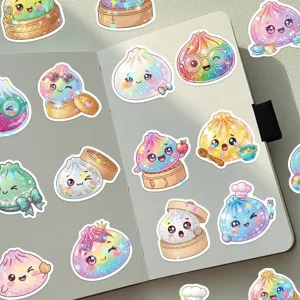 Overhead view of holographic dumpling stickers with cute faces scattered across an open notebook