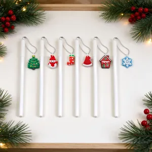 Flat lay of six white pens with silver chains and colorful Christmas charms on a festive surface