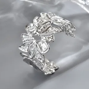 Vista obliqua di un bracciale aperto argentato, con farfalle in rilievo e texture finemente incisa