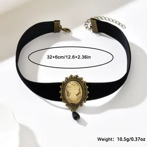 Choker in velluto nero disposto in piano, con cammeo decorato e pendente nero a forma di goccia