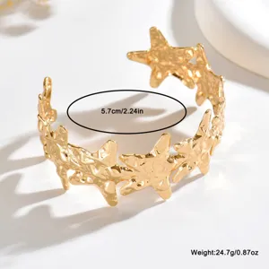 Primo piano delle stelle traforate martellate dorate sul bracciale aperto, diametro interno: 5,7 cm