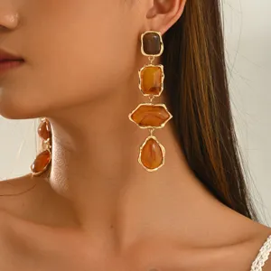 Primo piano di orecchini pendenti color ambra, forme irregolari e montatura dorata