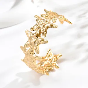 Primo piano di un bracciale aperto dorato con stelle marine unite e superficie martellata