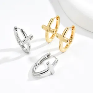 Tre orecchini a cerchio lucidi a forma di croce, argento e oro, su uno sfondo bianco luminoso