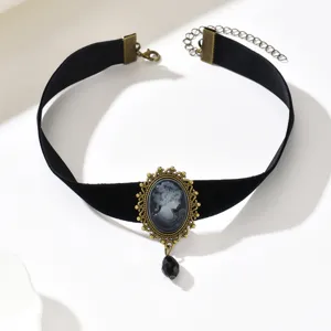 Dettaglio del nastro di velluto nero con cornice dorata traforata e ciondolo a goccia sfaccettato