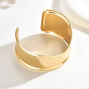 Bracciale rigido largo aperto color oro, con superficie a specchio liscia e terminali curvi