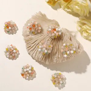 Six multicolored beaded round embellishments arranged around a seashell on a warm white backdrop