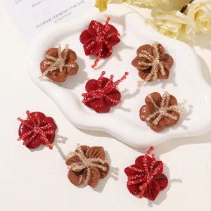 Overhead view of eight red and brown flower ornaments with beaded centers on a white tray