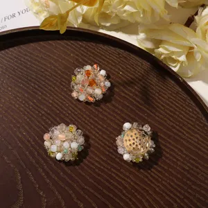 Three round bead ornaments in cream, pink and amber tones arranged on a dark wooden tray