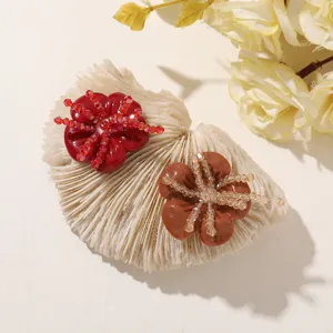 Red and brown resin flowers with sparkling bead centers, shown close-up on a textured surface