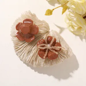 Close-up of two glossy brown resin flower accessories, one accented with clear bead strands