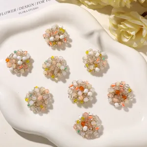 Eight pastel bead clusters arranged on a white wavy tray, with yellow flowers in the background