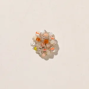 Clustered glass beads in clear, white, orange and pink tones, arranged as a small ornament