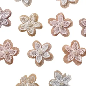 Fiorellini in pizzo beige e rosa con centro di perla, disposti in piano su sfondo bianco