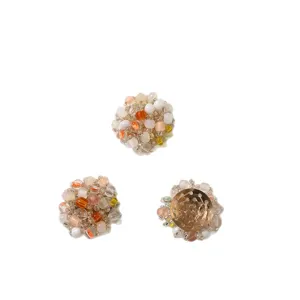 Three round multicolor beaded floral accessories, one showing its gold-tone backing on white