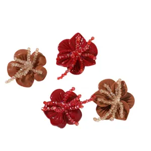 Four resin flower shoe charms with beaded centers in red and brown, arranged on a white background