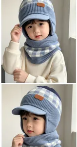Kind trägt eine blau-weiß karierte Strickmütze mit Ohrenschutz und passendem Strickschal