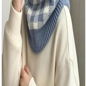 Nahaufnahme eines blau-weiß karierten Strickhalstuchs mit Rippkante auf cremefarbenem Pullover