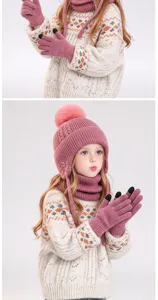 Kind met roze gebreide muts met pompon en oorflappen, bijpassende sjaal en touchscreenhandschoenen