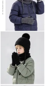 Kinderen dragen grijze gebreide handschoenen, een zwarte muts met pompon en een sjaal bij winterkleding