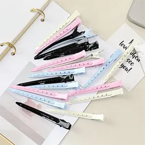 Flat lay of duckbill hair clips in pink, blue, ivory and black, with perforated metal grips