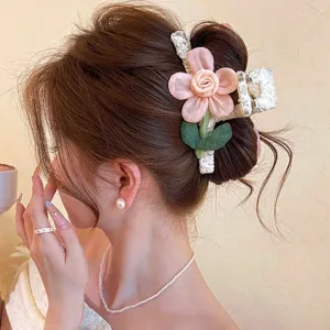 Side view of a woman wearing a white lace-textured hair clip with a pink flower and green leaves