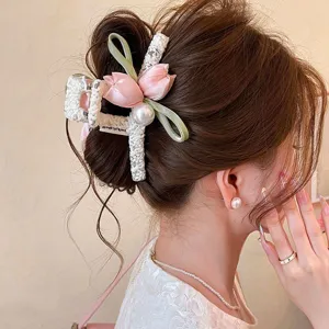 Close-up of a white lace hair clip with pink flowers, green ribbon and pearl in a styled updo