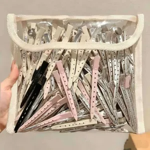 Perforierte Haarspangen in Silber, Creme, Rosa und Schwarz, in einem durchsichtigen Netzbeutel