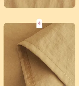 Close-up van okergele schortstof met fijne textuur, gestikte rand en een zichtbare binnenbies