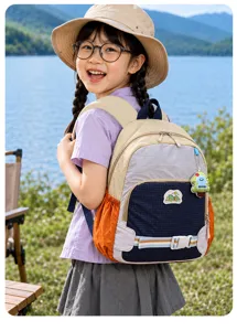 Enfant portant un sac à dos multicolore avec poche latérale orange et pendentif au bord d’un lac