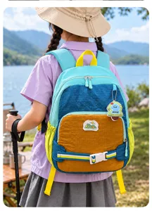 Vue extérieure d’un enfant portant un sac coloré avec un porte-clés, au bord d’un lac