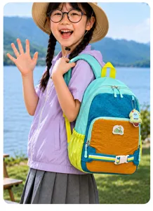 Au bord d’un lac, un enfant porte un sac à dos coloré avec sangle à boucle et panneaux contrastés