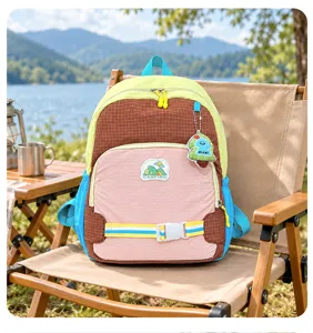 Sac coloré à poche quadrillée et écussons ludiques, présenté en camping au bord du lac