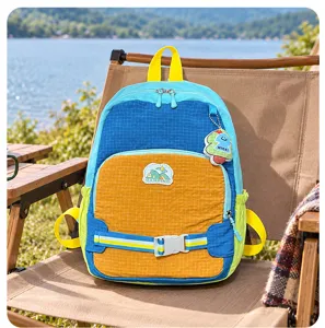 Sac à dos coloré avec poches zippées et boucle, posé sur une chaise de camping près d’un lac