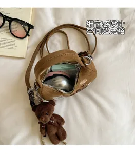 Détail du sac marron ouvert, effet daim, avec intérieur spacieux zippé et breloque ourson en peluche