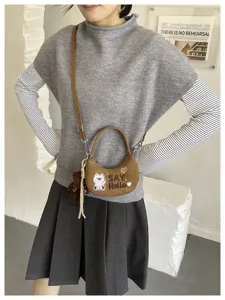 Sac marron à texture veloutée porté en bandoulière, avec ours brodé, « SAY Hello » et breloque